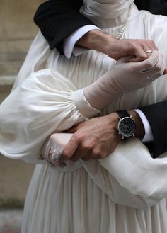 a man and woman dressed in white holding hands