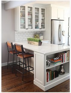 a kitchen with white cabinets and an island that has bookshelves on top of it