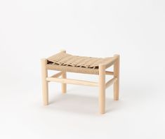 a small wooden bench with woven seat padding on the back and sides, against a white background