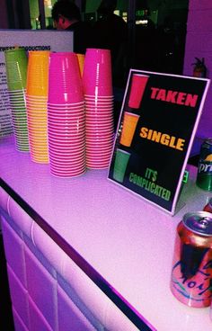 there is a table with neon colored cups on it and a sign that says taken single