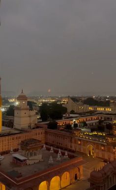 an aerial view of a city at night with buildings lit up in the distance and lights on