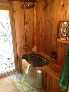 a bath tub sitting inside of a bathroom next to a wooden wall with a window