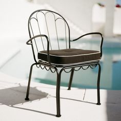 a chair sitting next to a swimming pool in the sun with no one around it