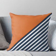 an orange and blue throw pillow sitting on top of a couch