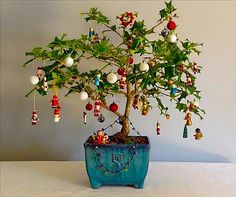 a bonsai tree with ornaments hanging from it's branches on a white table