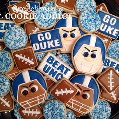 cookies decorated like football players are on a black plate with blue and white frosting