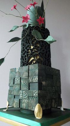 a three tiered cake decorated with flowers on top of a green tablecloth covered shelf