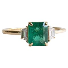 Metal: 14K Yellow Gold Stone: Zambian Emerald Stone Weight: 1.17 Carat Side Stones: Natural Trapezoid Diamonds Diamond Color and Clarity: F, VVS-VS Diamond Weight: 0.17 total carat weight Band Width: 1.5mm x 1.5mm Green Engagement Rings, Zambian Emerald, Vs Diamond, Emerald Stone, Zambia, Three Stone Rings, Emerald Diamond, Three Stone, Stone Rings