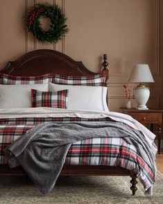 a bed with plaid comforter and pillows in a brown room next to a wreath on the wall