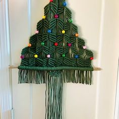 a christmas tree made out of yarn and beads on a door hanger in front of a white door