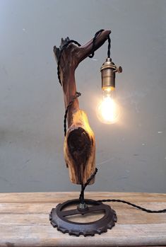 a wooden table lamp with a light bulb on it's side and a chain around the base