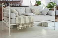 a living room with a white couch and some potted plants on the shelf next to it