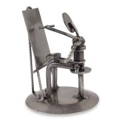 a metal sculpture of a person sitting in a chair