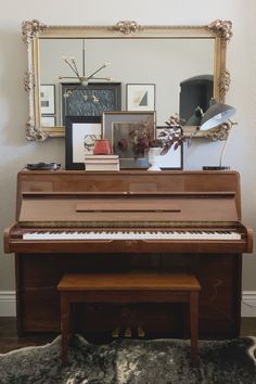 a piano sitting in front of a mirror on top of a wooden floor next to a rug