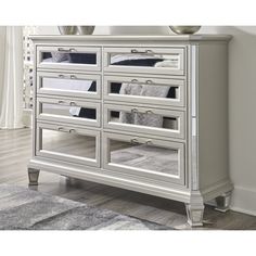 a white dresser with mirrored doors and drawers