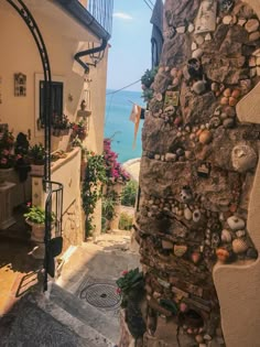 an alley way with stone walls and stairs leading to the ocean