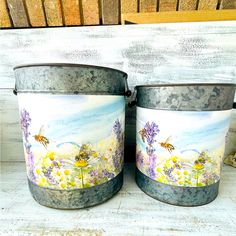 two buckets painted with flowers and bees on them