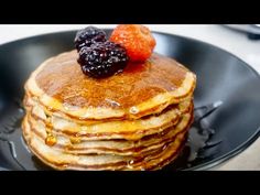 a stack of pancakes with syrup and fruit on top are sitting in a black plate