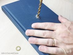 a person is holding onto a blue book with a drill bit in the middle of it