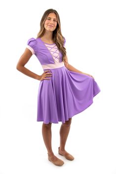 a girl in a purple dress posing for the camera with her hands on her hips