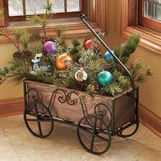 a wagon filled with christmas ornaments on top of a wooden floor next to a window