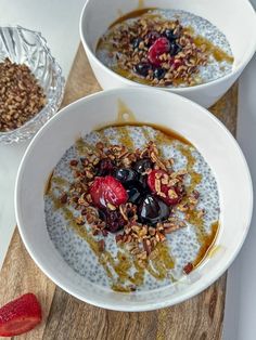 two bowls filled with oatmeal and fruit on top of a wooden table