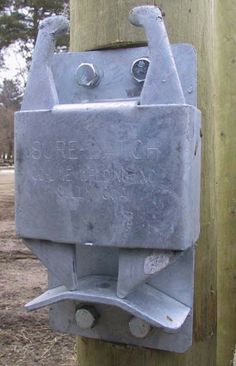 an old metal box attached to a wooden pole with two screws on the end