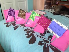 pink and purple bags with name tags on them are sitting on a bed next to a black cat