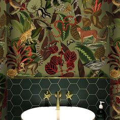 a bathroom with green and red wallpaper, gold faucet, and white sink