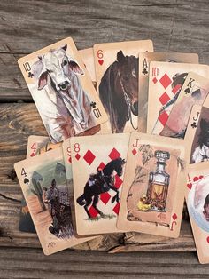 playing cards with pictures of horses and animals on them are laid out in front of a wooden background