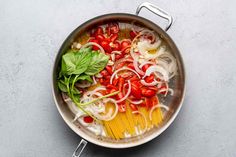 a pan filled with pasta and vegetables on top of a table