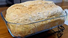 a loaf of bread in a glass dish on a wooden table with a napkin and fork