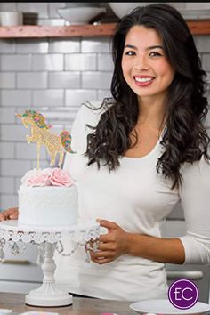 a woman standing in front of a cake on top of a white plate with pink frosting