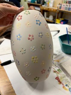 an egg is being painted with flowers on the outside and inside, sitting on a table