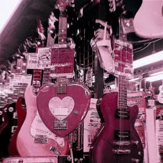 guitars are displayed in a store window with pink and red colors on them, as well as other items