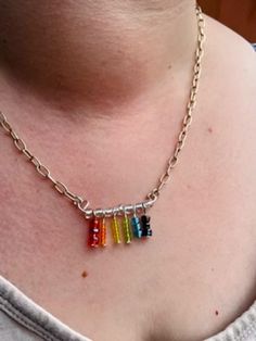 a woman wearing a silver chain necklace with four different colored beads hanging from it's sides