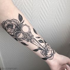 a woman's arm with flowers and scissors tattooed on the left side of her arm