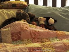 two stuffed animals laying on top of a bed