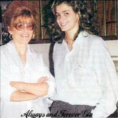 two women standing next to each other with their arms crossed