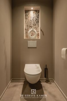 a bathroom with a toilet and a painting on the wall