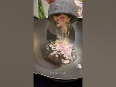 a person in a hat is pouring something into a pan with food on it and sprinkles all over the top