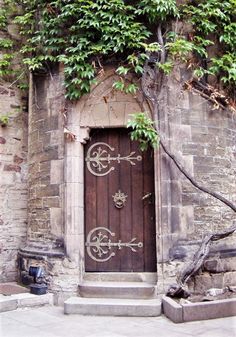 an old door with vines growing over it and stone steps leading up to the entrance