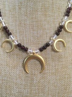 "Ancient style Lunula or Crescent moon necklaces with a variety of genuine gemstone options! Beautiful 22k gold plated pendants to compliment your ancient Roman, Greek, Parthian, Coptic or any other Bronze age persona! You can wear them with your prettiest T shirt and jeans outfit. Earrings that compliment these necklaces can be found in my Etsy shop here. https://www.etsy.com/listing/817662134/ancient-style-lunula-crescent-mooref=shop_home_active_2 These necklaces are finished with 14k gold fil Gold Crescent Gemstone Jewelry, Gold Jewelry With Moon Charm And Round Beads, Crescent Moon Charm Amulet Jewelry, Spiritual Crescent Brass Jewelry, Spiritual Crescent-shaped Brass Jewelry, Gold Crescent Spiritual Necklace, Celestial Crescent Jewelry For Meditation, Celestial Crescent Jewelry For Healing, Spiritual Gold Crescent Necklace