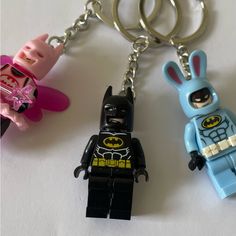 two lego keychains with batman and bunny ears on them are laying next to each other