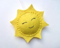 a yellow felt sun ornament hanging on a white wall with eyes drawn on it