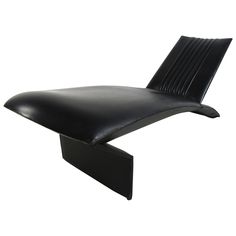 a black leather lounge chair sitting on top of a metal base