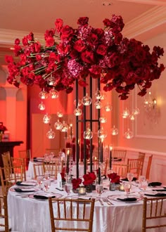 a tall vase filled with red flowers sitting on top of a table