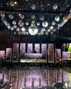 an empty stage with disco balls hanging from the ceiling and lights reflecting on the floor