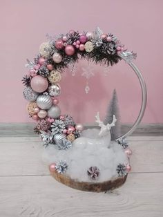 a pink and silver christmas wreath on top of a wooden table