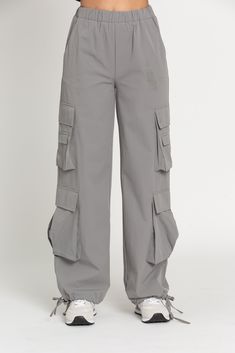 NEW Limited Edition & custom designed Dusty Grey Parachute Pants! Not only did we spend months designing these amazing cargo style pants, but we PERFECTED them in the process! These pants are insanely versatile due to their lightweight material and trendy style. They feature adjustable ankle cuffs that you can leave wide or tie up for a jogger look. The elastic waist-band allows for a comfortable fit and the multiple pockets provide great functionality. These pants easily can be worn for any wor Cheap Nike Sportswear Bottoms, Vintage Nike Pants Old, Grey Parachute Pants Outfit, Highschool Supplies, Aesthetic Highschool, Grey Parachute Pants, Gold Hinge Skirt, Parachute Pants Outfit, Grey Cargo Pants